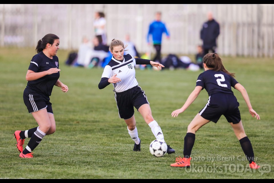 Holy Trinity Academy Knight Brielle Masse dribbles between Falcons Meghan Dhaliwal and Kate Kennedy in the FAC girls soccer final Oct. 15 at Riverside Park. (BRENT CALVER/Western Wheel)