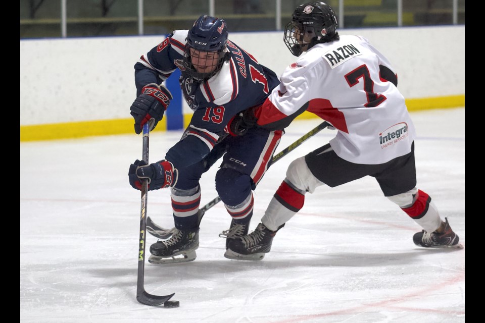 Carstar Okotoks Bisons forward Sam Callahan slips by Airdrie Thunder blueliner Ethan Razon during the 10-0 win for Okotoks on Jan. 23 at the Murray Arena. Callahan scored a hat trick in the victory.