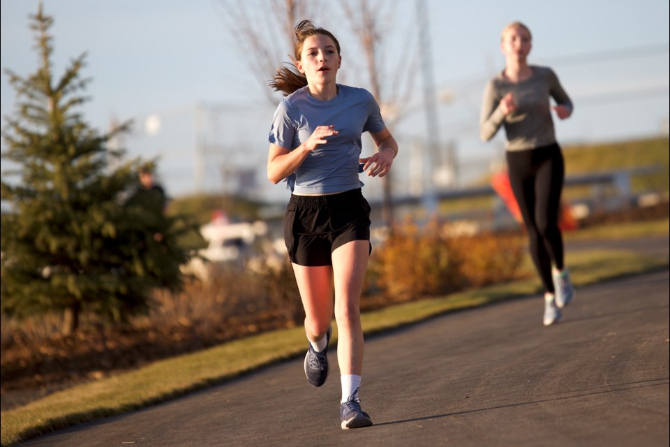 Molly Bishop and Anna Asseltine run the pathways during the Okotoks Track and Cross Country Club's fifth and final run of its fall race series around the Wedderburn Pond in Okotoks on Oct. 29. 