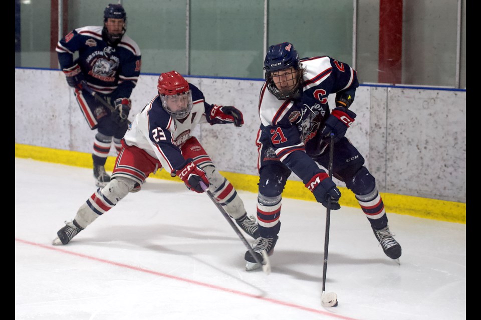 Carstar Okotoks Bisons captain Jake Snashall protects the puck from Cannex Cochrane Generals defenceman Zach Wilkins during Game 3 of the HJHL South Semifinal on Feb. 28 at the Murray Arena. 