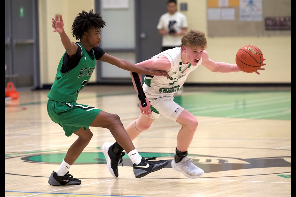 Holy Trinity Academy Knight Noah Barlow is defended by St. Mary's Saints guard Prynce France during the final of the Knights Classic on Jan. 11 at HTA. St. Mary's, the top ranked 4A team in the province, won by a 76-60 score. 