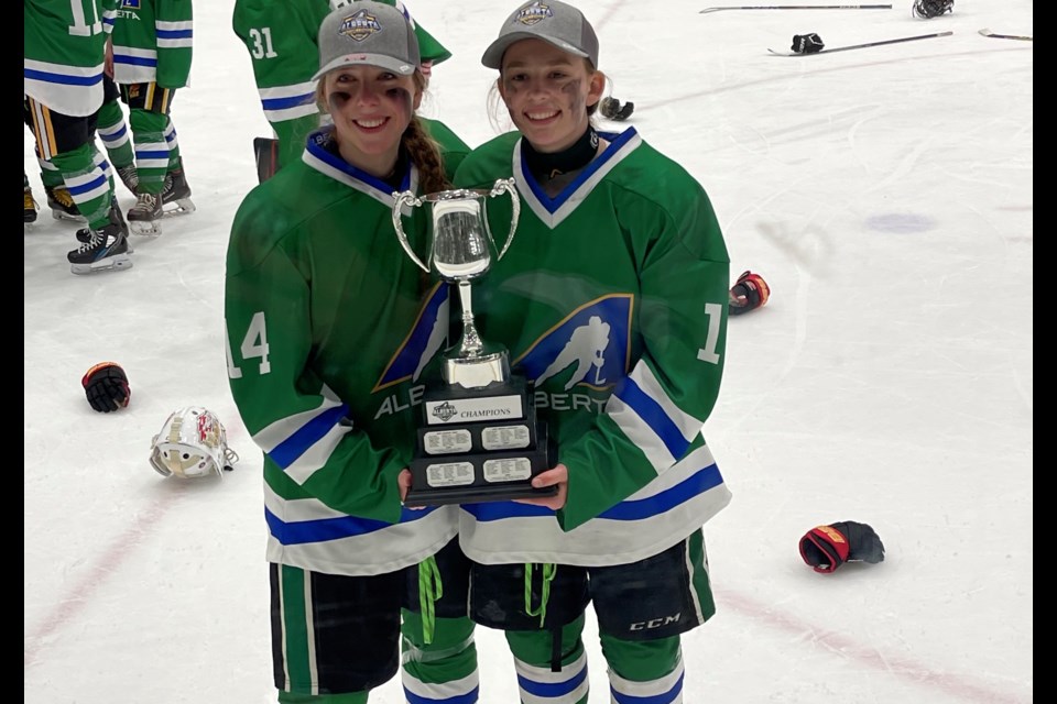 Rocky Mountain Raiders forward Brynn Evans (left), of Strathmore, and Ella Simard, of Okotoks, pose with the Alberta Challenge trophy after winning the U15 female hockey event as members of Team Green on May 7 at the Gary W. Harris Canada Games Centre in Red Deer. 