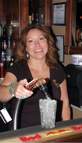 Okotoks server Rayna Crossan pours a drink at the George Traditional House. She said she won&#8217;t complain about a system setting different minimum wages for people who