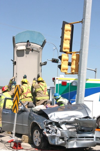 Firefighters lift off the roof of a car while another firefighter stabilizes the head of a woman who was trapped inside following a collision at Southridge Drive and Big Rock 