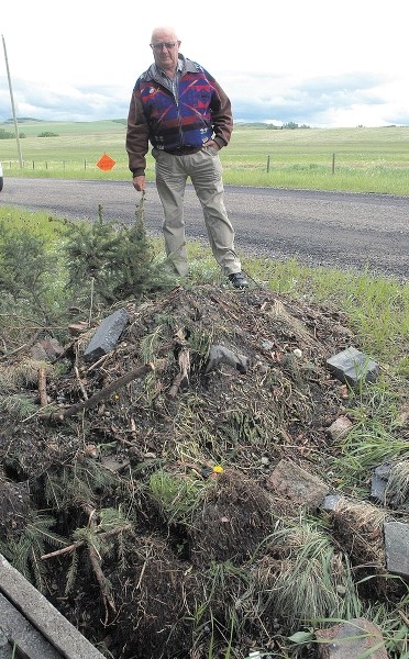 MD of Foothills rancher Doug Fraser surveys garbage left near his property earlier this year. MD council is considering a maximum $10,000 fine for illegal dumping.