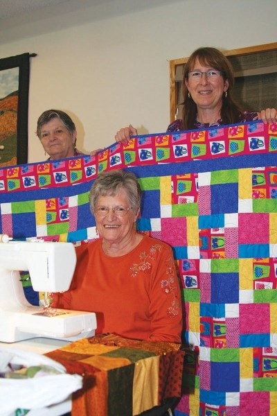 Linda Bandy, Sue Knowler and Clairie Leitch work on some quilts at the Chinook Quilters regular work bee at the Okotoks Anglican church on June 3. The group is hosting a show 