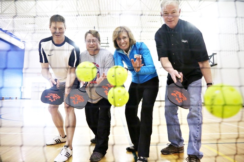 Tim Arnholz, Patty Van Winkle, Janette Messer, and Mark Doherty with the Town play with pickleball equipment at the Okotoks Recreation Centre. The activity will be one of