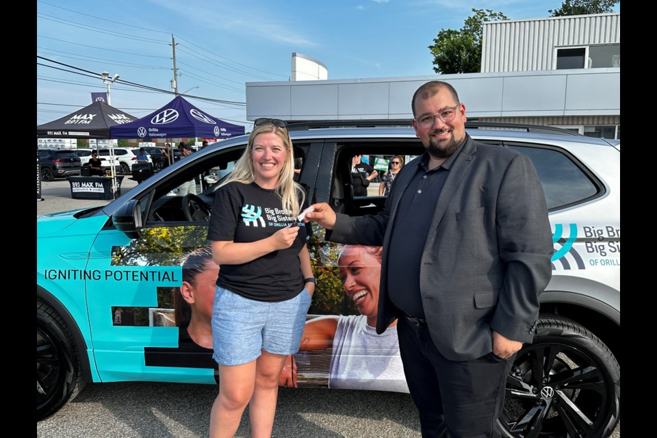 Orillia Volkswagen general manager, Dustin Stein, gives Big Brothers Big Sisters of Orillia and District's Miranda Chaffey the keys to the organizations new Volkswagen Tiguan.