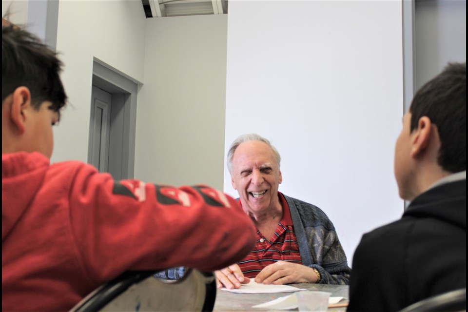 John Dunn is shown Wednesday with students from Mnjikaning Kendaaswin Elementary School during the Seniors in the Studio program at the Orillia Museum of Art and History. Nathan Taylor/OrilliaMatters