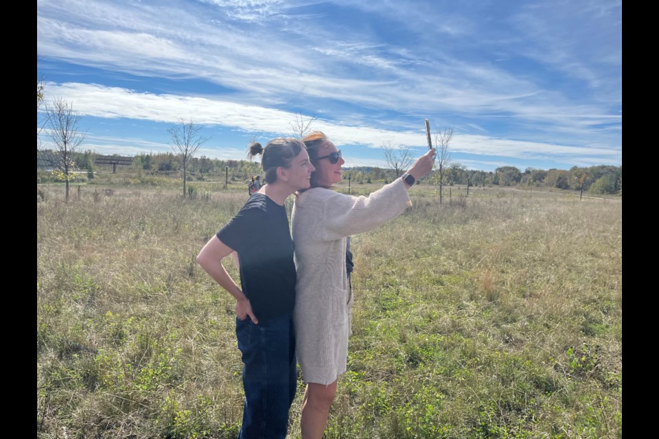 Arts Orillia artistic director Kate Hilliard and Heidi Strauss, artistic director of adelheid, use a phone to experience a community art project called You Are Swimming Here.