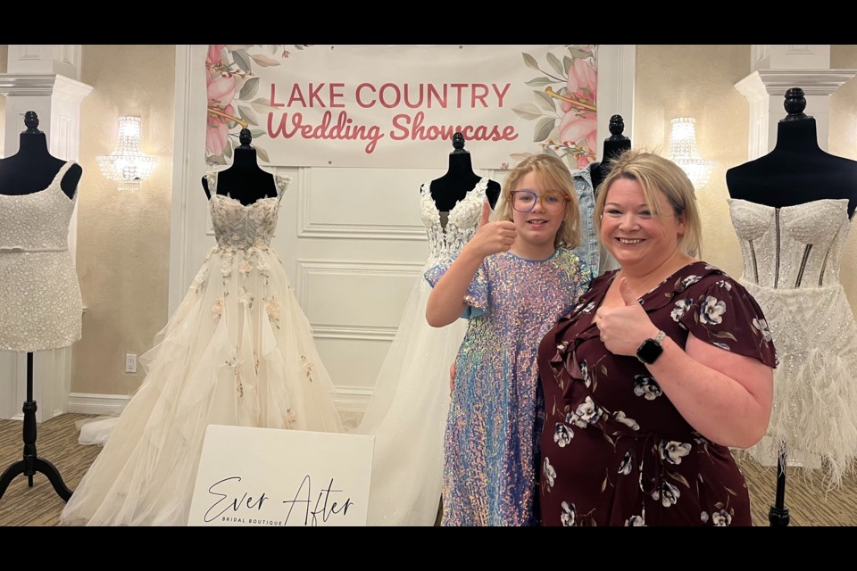 Shelby Stock, right, and her daughter pose in front of wedding dresses at the Lake Country Wedding Showcase she organizes twice a year.