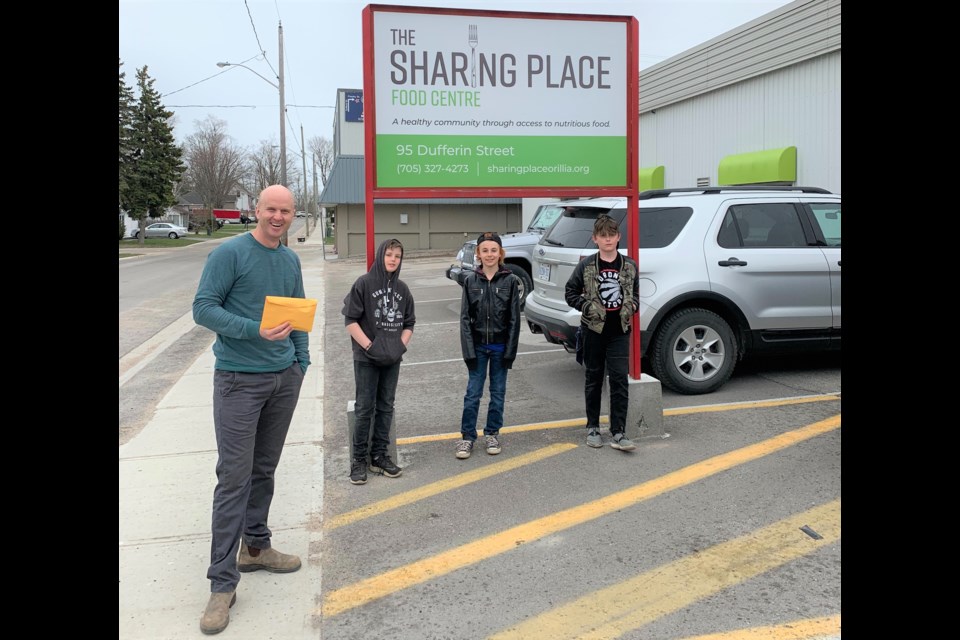 Chris Peacock, executive director of The Sharing Place Food Centre, was all smiles as he received the $1,040 raised by members of the band Seven Days Past, from left, Cole Perreault, 10, Carter Perreault, 11, and Tanner Greenwood, 10. Supplied photo
