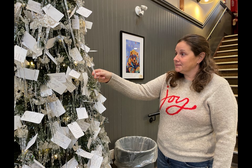 Volunteer Angie Walsh looks at the ornaments and messages on the Angel Tree at Mariposa Market. She left her own tag for her lost loved ones.