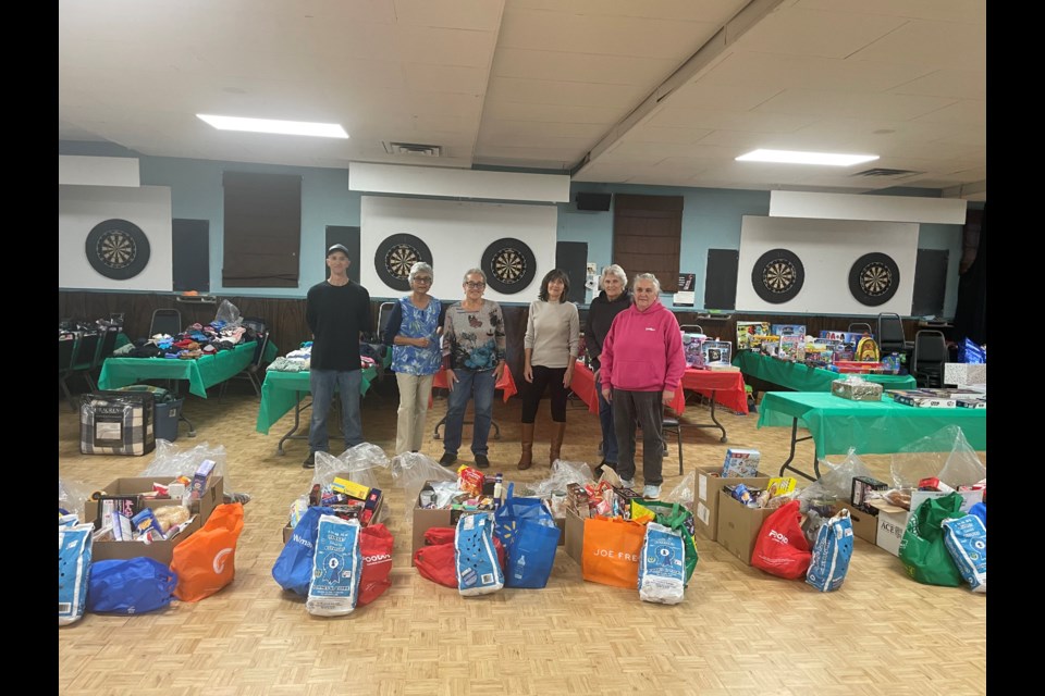 Volunteers stand behind bags and boxes of donated food ready to be given to families in need as part of the Feeding Families campaign.