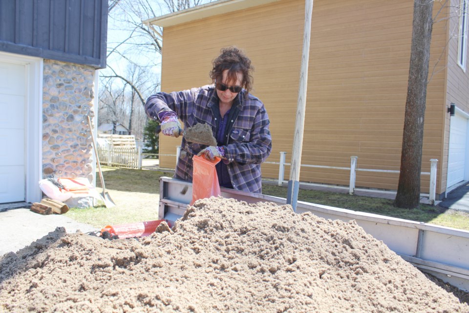 Kathy Frank fills sandbags to protect her Peninsula Point Road home from the rising Severn River. Nathan Taylor/OrilliaMatters