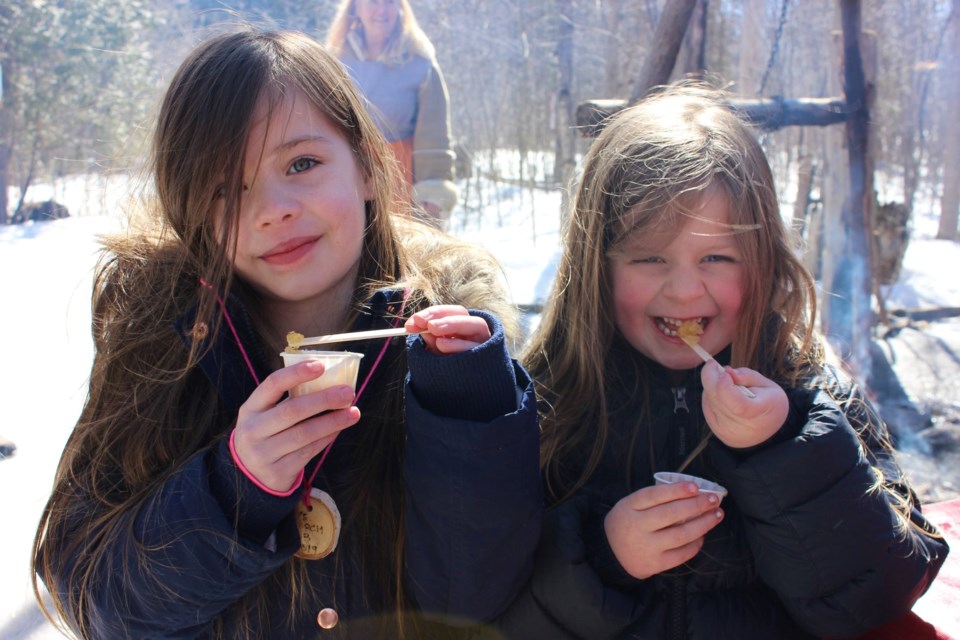 Two young guests enjoying maple taffy at the Sweetwater Harvest Festival.