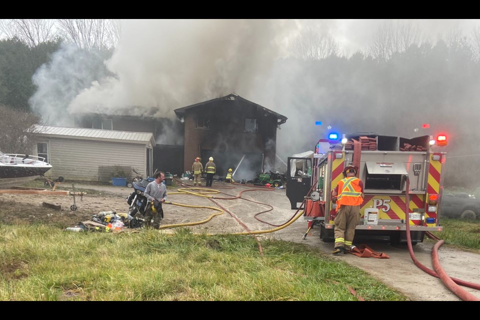 Oro-Medonte Township firefighters work to douse a fire on Highway 12 near Dunn's Lane Tuesday morning.