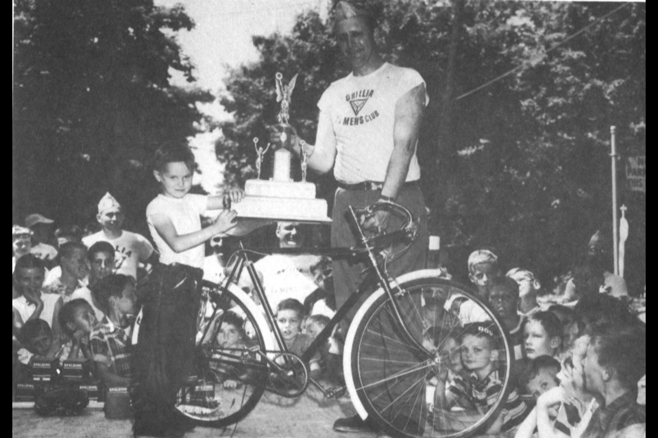 Russ Jerome presents the Soapbox Derby Trophy to little Ricky Ley, Winner of the grand prize at the Y’s Men’s Soap Box Derby