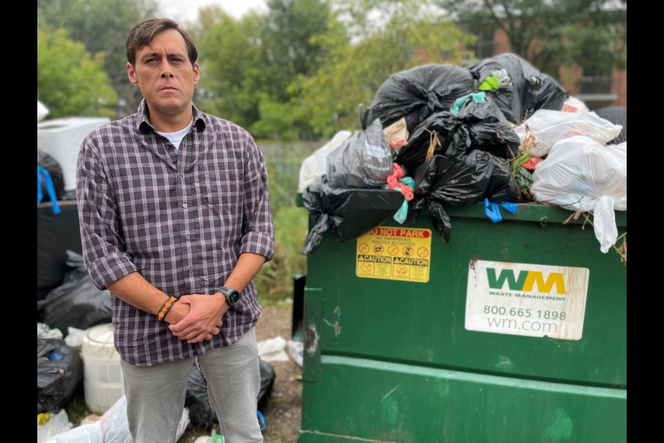 Tyler Shepperdson stands beside an overflowing dumpster at 135 Atherley Rd. He said conditions at the complex have deteriorated since a new owner took over — to the point he has decided to move.