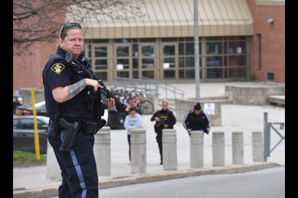 An OPP officer stands guard at Twin Lakes while a female student makes her way, with police, out of the school. Dave Dawson/OrilliaMatters