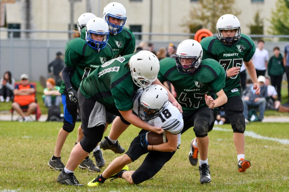 Matthew Clark, a member of St. Theresa's junior football team, gets tackled to the ground by a wall of Patrick Fogarty players during the homecoming game Friday at the Orillia school