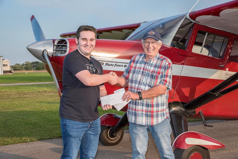 COPA Flight 149 Captain Adrian Verburg presents Ethan Foster with a $1000 flight training bursary.