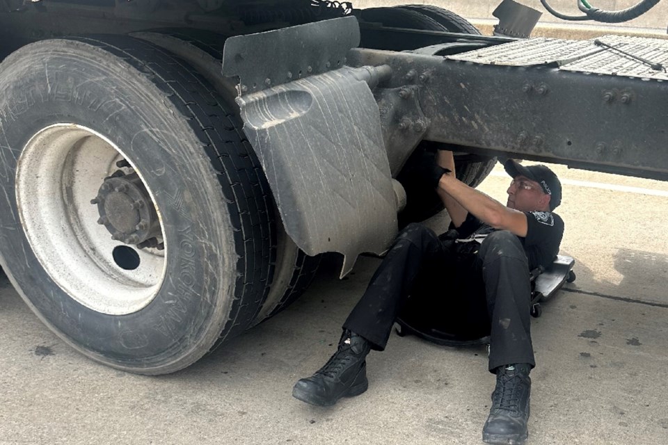 A police officer inspects a commercial truck as part of a joint safety initiative.