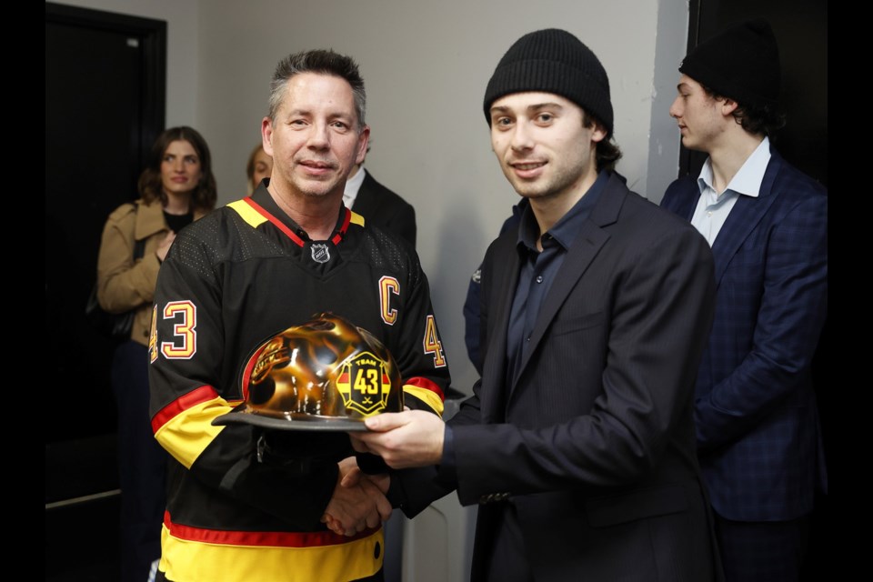 NHL star Quinn Hughes (right) accepts a custom helmet from Whistler Fire Chief Thomas Doherty on Oct. 30, 2024.