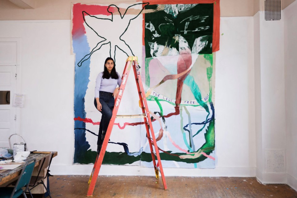 Vancouver artist Russna Kaur poses next to one of her paintings.