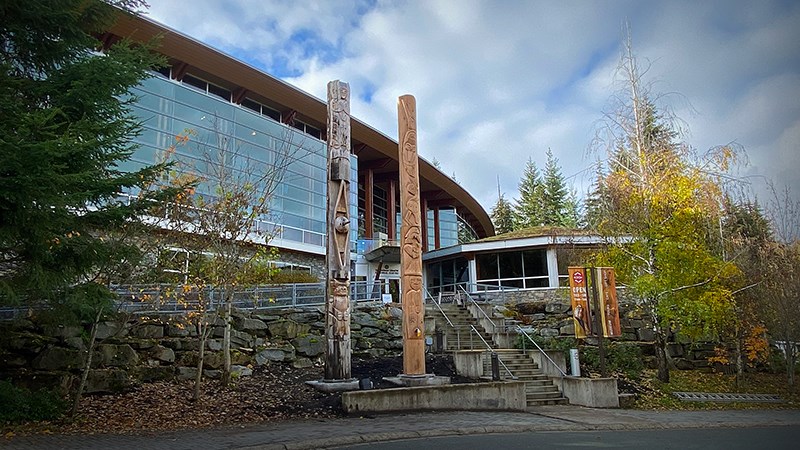 The Story Pole carved by Jonathan Joe and Redmond Andrews (right) stands outside the Squamish Lil'wat Cultural Centre next to the House Post by Xwalacktun and Brandon Hall.