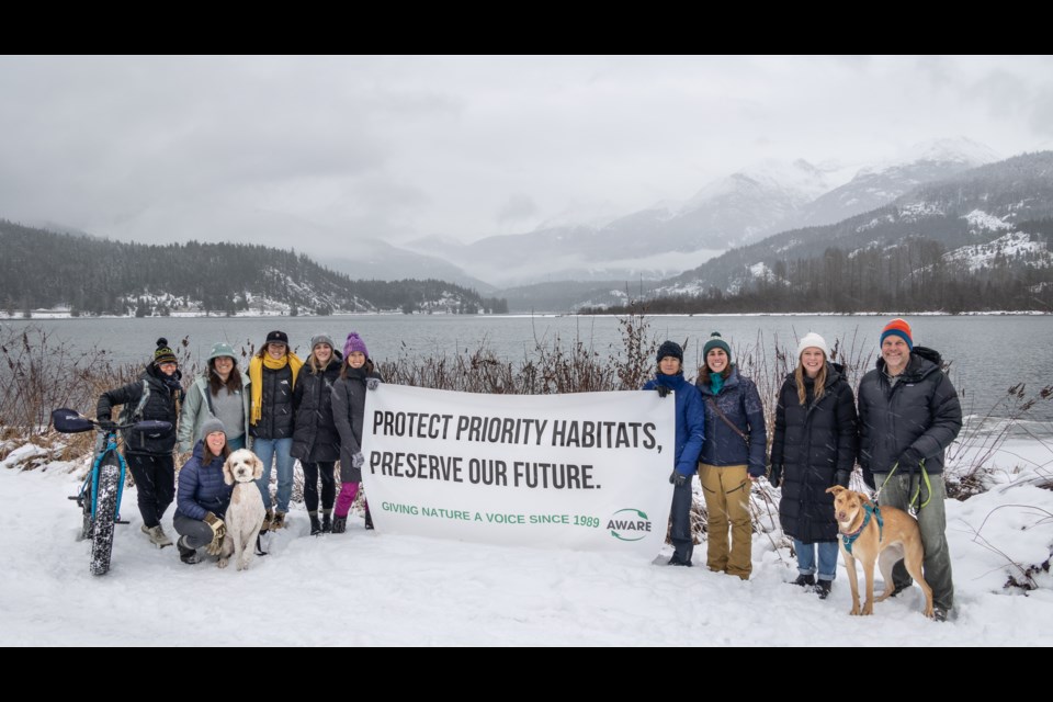 Community members hold a sign in front of Green Lake’s riparian area that was illegally trimmed. Sea to Sky MLA Jeremy Valeriote is the furthest to the right. 