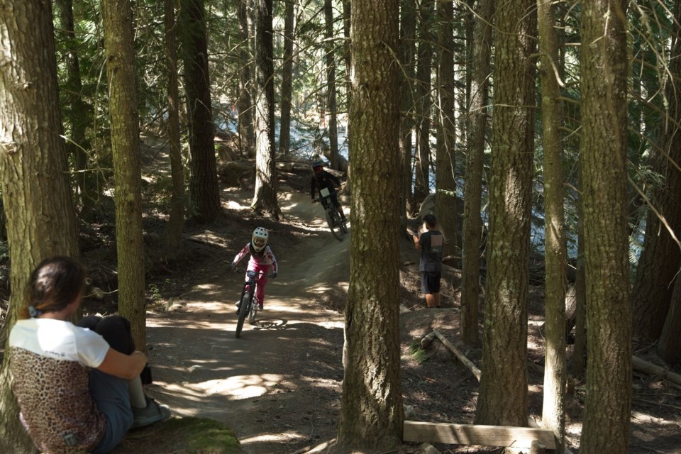 A girl watches a biker race at the 2024 Kidsworx Enduro.