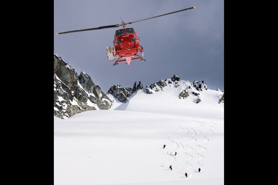 A Wildcat Helicopters aircraft flies overhead as a group of heli-ski clients hit the snow in Whistler.