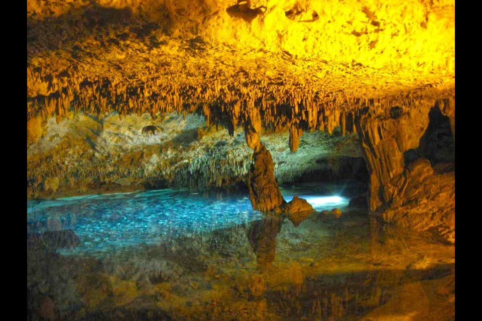 Fixed lights cast golden and aqua glows on the passages of Rio Secreto's semi-sunken cenote inside Mexico's Yucatan peninsula. Photo by Lynn Martel