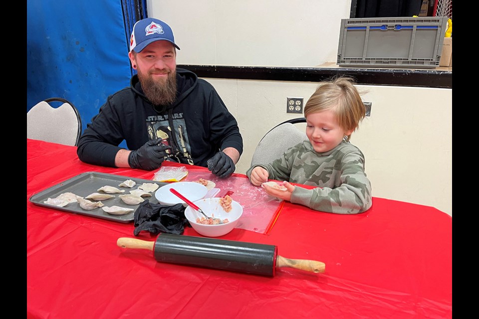 FOOD PREPARATION: Henderson Elementary School student Hayden Nimmo [right], with his father Nigel, makes dumplings at the school’s community Lunar New Year celebration, which provided traditional foods for the community dinner.