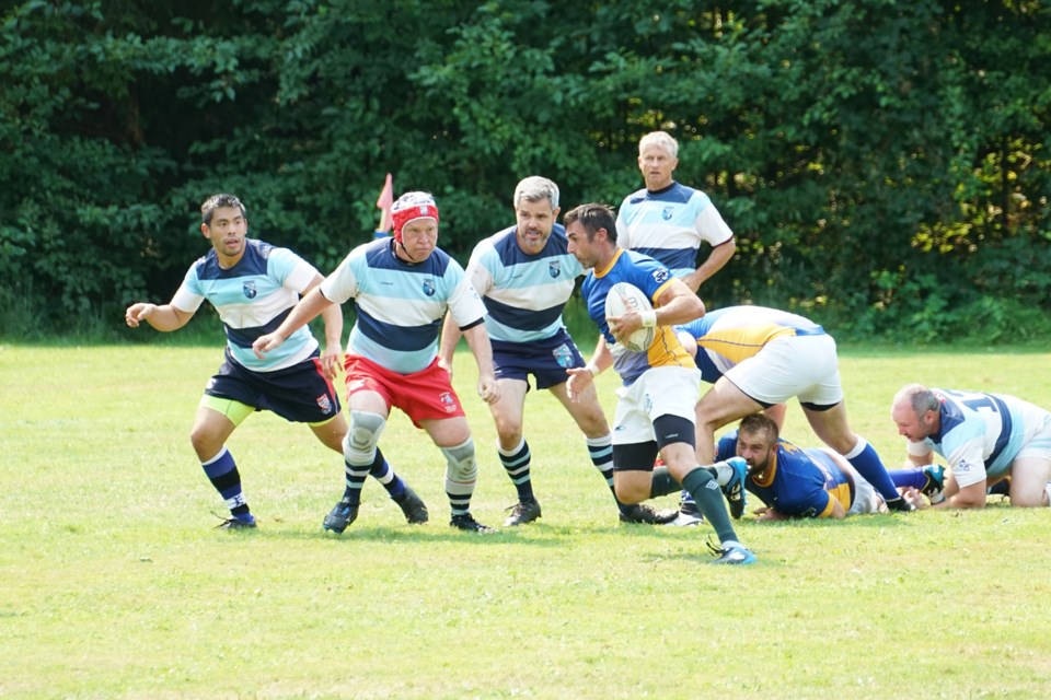 EXHIBITION MATCH: Swarmed by Burnaby Twilighters players, an Otago Rugby Club Old Boys player takes the ball and dashes up field. The Burnaby side won the exhibition game three trys to one.