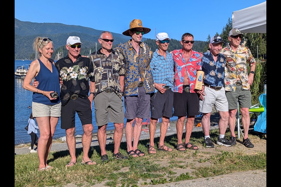 Finish line awards following the 2024 Knee Knackering North Shore Trail Run were presented to participants who have finished the race 25 times. [From left] Kelsy Trigg, race director; Neil Wakelin (28); Keith Wakelin (29); Mark Grist (26); Peter Findlay (25); Ean Jackson (30); Ron Adams (26); and Enzo Federico, race co-founder.