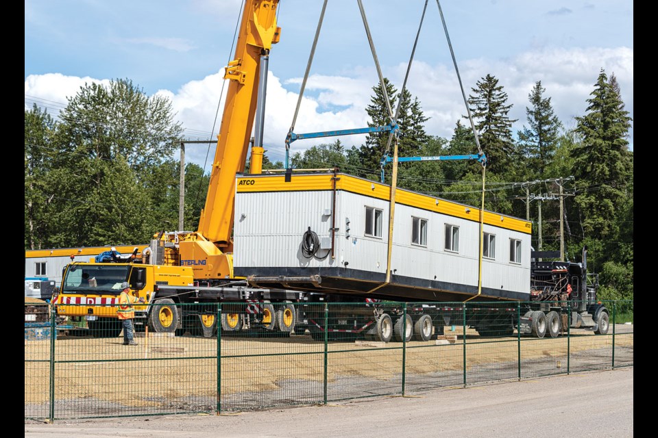 A crane lifts a trailer from a truck so it can be prepared as part of the 44-unit transitional housing project by BC Housing and the City of Prince George being put in place near Moccasin Flats on Tuesday, June 25, 2024 in Prince George, B.C.