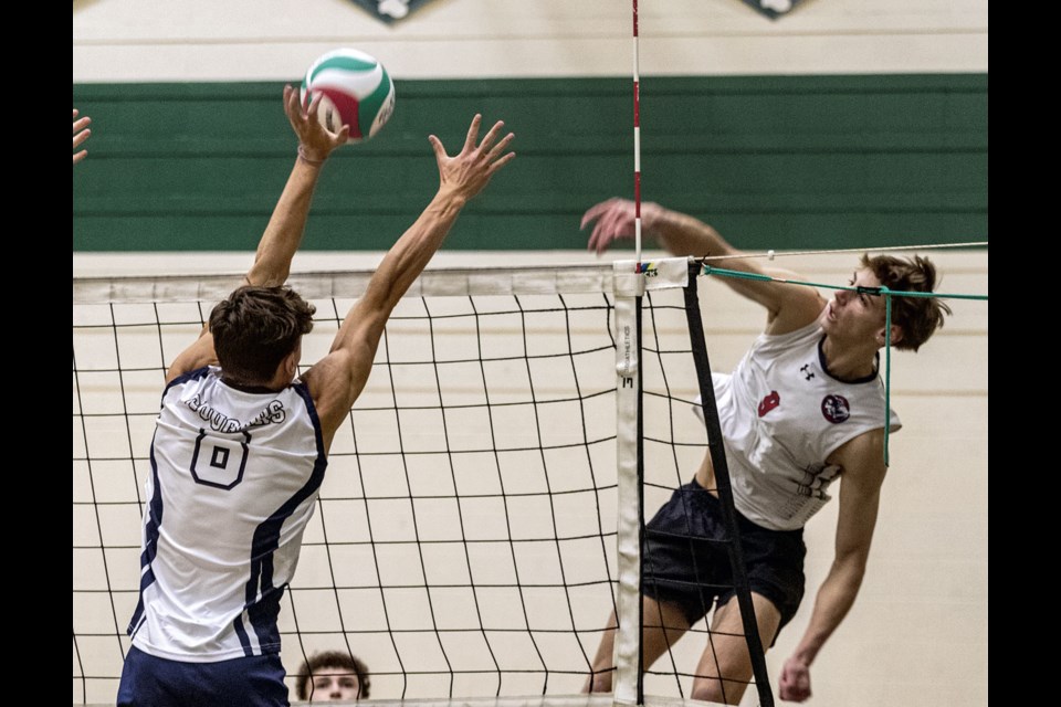 CHSS Cougar Angus MacFarlane attempts to block a spike by D.P. Todd Trojan Zac Kynoch in their game Friday night in the senior boys volleyball tournament held at PGSS.