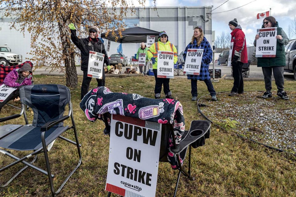 CUPW members wave to honking trucks as they strike along Penn Road in front of the mail sorting facility Friday.