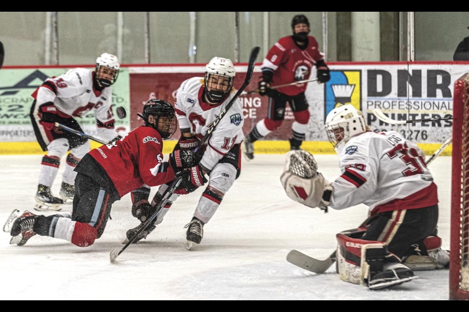 North West Hawks forward Daniel Tong falls into blocking Cariboo Cougar defenseman Josh Gendron as Cougars goalie Andrik Lygas deflects his shot Saturday March 15 at kin 1.