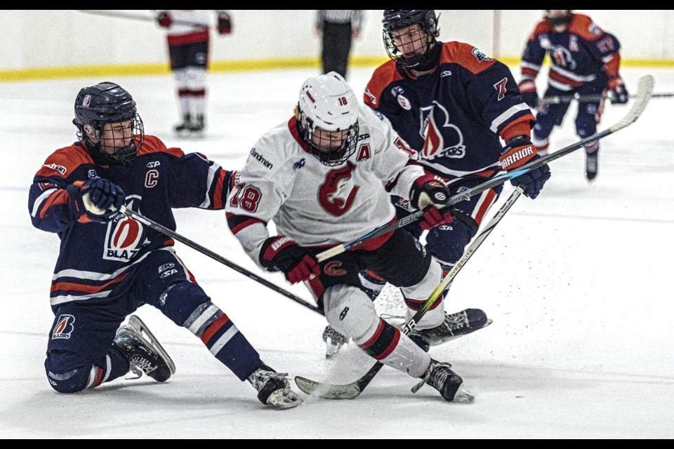 Cariboo Cougars forward Jack Tidsbury goes down as he gets his legs tangled in the sticks of Thompson Blazers Roman O'Regan and Luca Cupello Saturday, March 8, 2025 at Kin 2.