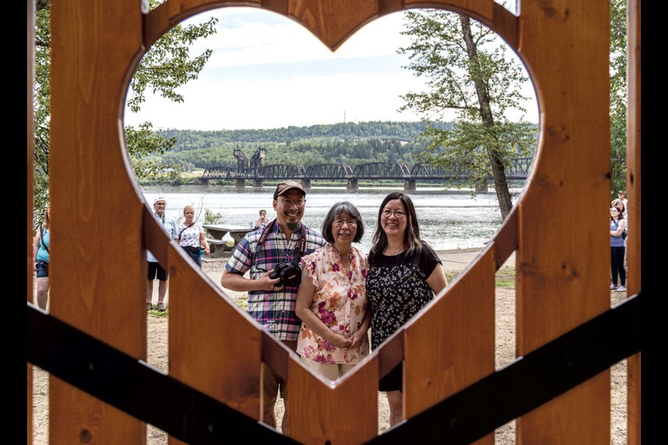 Susan Chin, flanked by children Alexander and Leanne, poses in front of the Chuck Chin Memorial Bench at Cottonwood Island Nature Park Sunday.