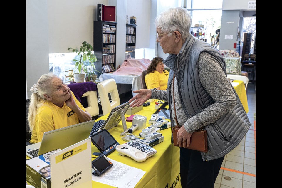 Robin Warrington discusses accessibility aids with CNIB volunteer Kathleen Jordan at the CNIB Prince George Mobile Hub held at the Q3 Creative Hub at Third Avenue and Quebec Street Thursday. 