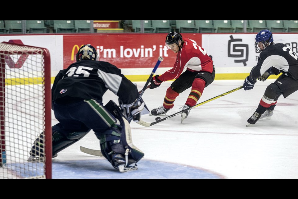 Bauer Dumanski of Team Connoly (red) tries to steady the puck while warding off Brody Bohemier of Team Chara during their training camp scrimmage Friday at CN Centre Friday.