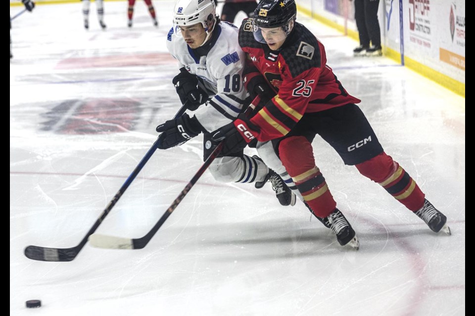 Cougars defenseman Arseni Anisimov and Wild forward Shaun Rios battle shoulder to shoulder for control of the puck Friday March 14 at CN Centre.