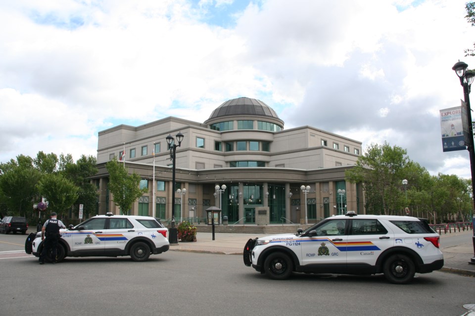 RCMP officers surround the courthouse on George Street after a bomb threat was received on Tuesday, July 30, 2024 in Prince George, B.C.