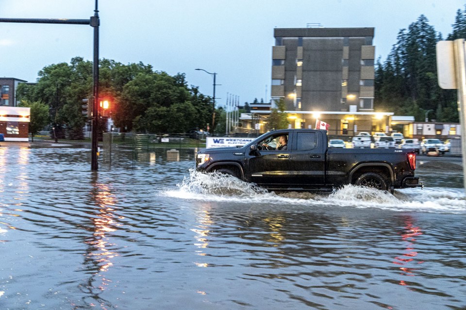 A pickup truck enters the intersection of Dominion and 7th Avenue after heavy rain Monday evening created flooding up to a foot deep.