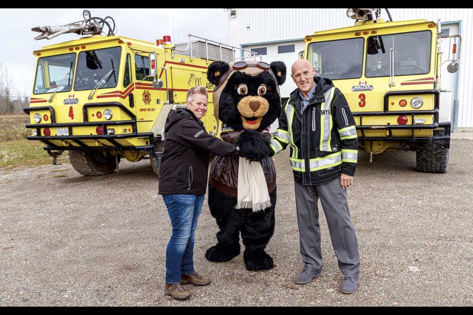 Prince George Airport Authority (PGAA) mascot Amelia Bearheart puts her seal of approval on the deal as Barkerville general manager Carrie Chard and PGAA CEO and president Gord Duke in front of the two Waltek Aircraft Rescue Fire Fighting trucks at YXS Wednesday.