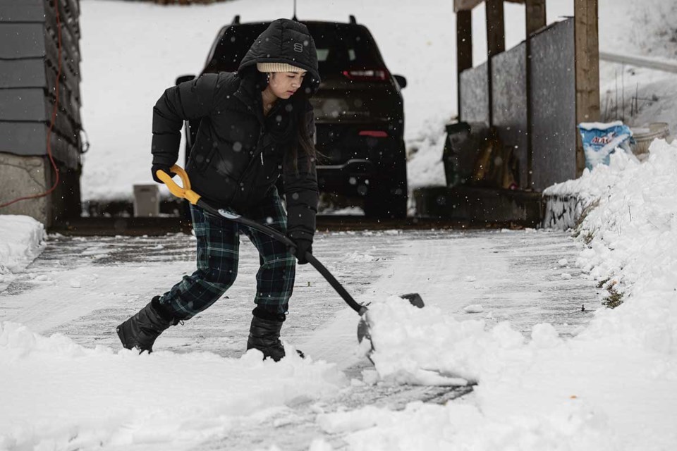 Trisha Magtoto, 20, deals with the wet heavy snow that fills her Lorne Crescent driveway Saturday as she prepares to leave for work.